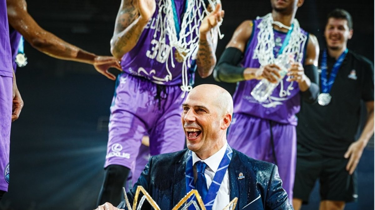 Peñarroya, empapado, celebra aún el podio el triunfo con la copa a sus pies. FIBA