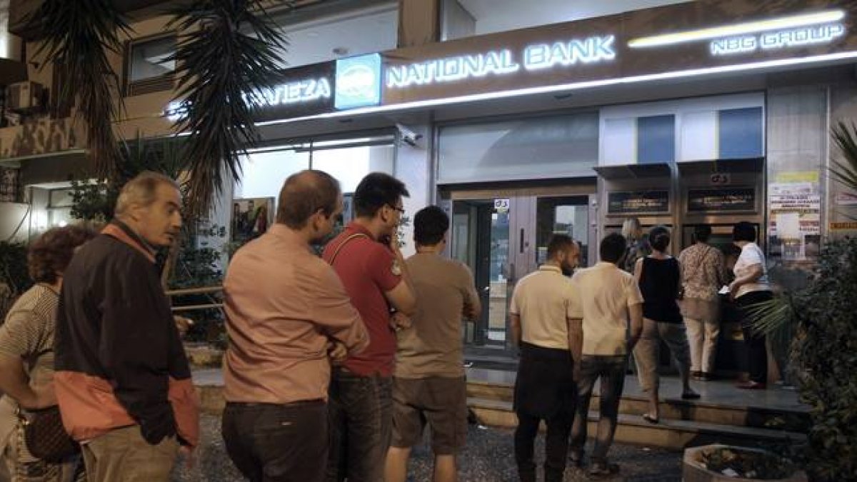 Ciudadanos griegos hacen cola ante el cajero del Banco Nacional de Grecia, en Atenas, esta madrugada.-Foto: SIMELA PANTZARTZI / EFE