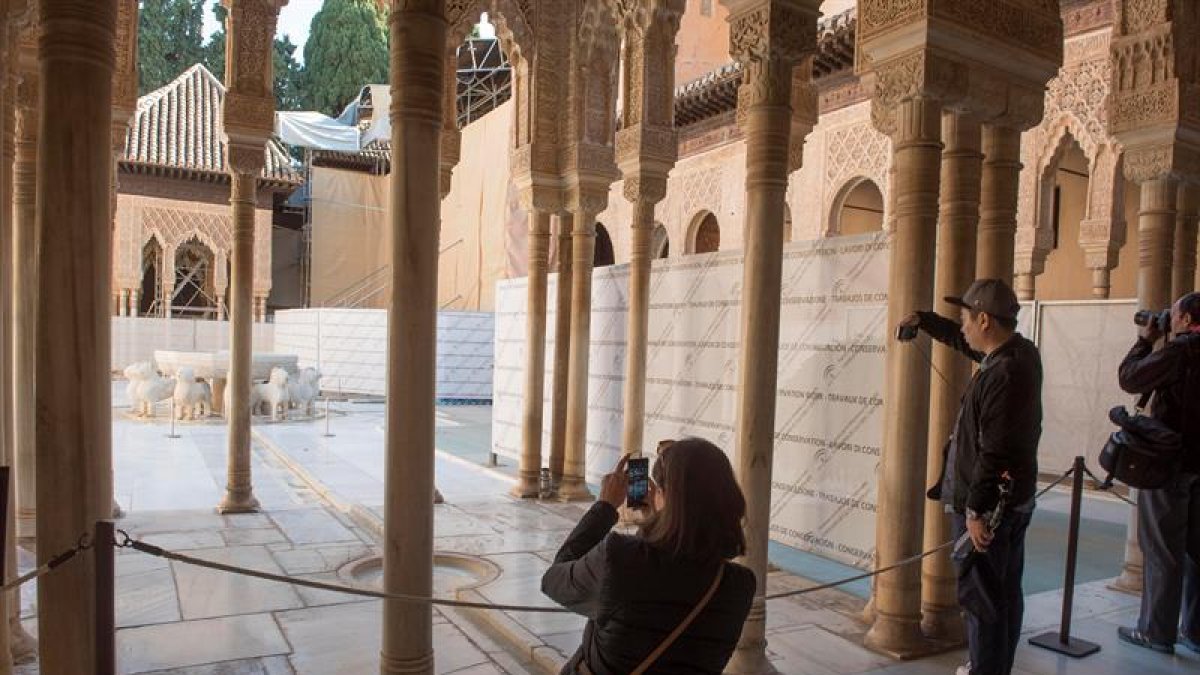 Unos turistas fotografían el Patio de los Leones de la Alhambra de Granada.