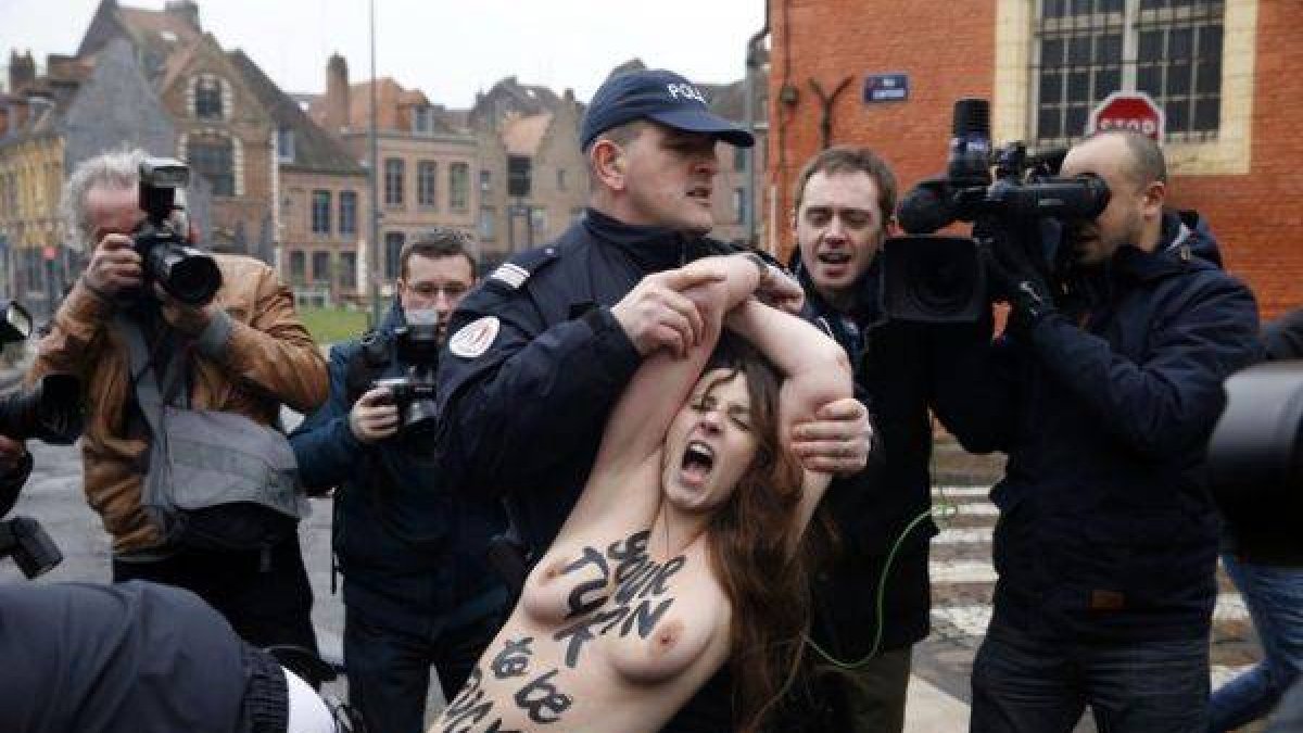 La policía francesa se lleva a rastras a una de las activistas de Femen que ha asaltado el vehículo de Strauss-Khan a su llegada al juzgado, este martes.-Foto: REUTERS / PASCAL ROSSIGNOL