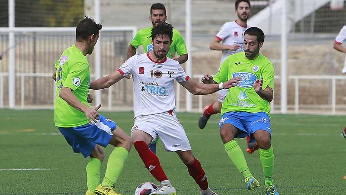 David Fernández conduce el balón acosado por dos jugadores del Almazán-Raúl G. Ochoa