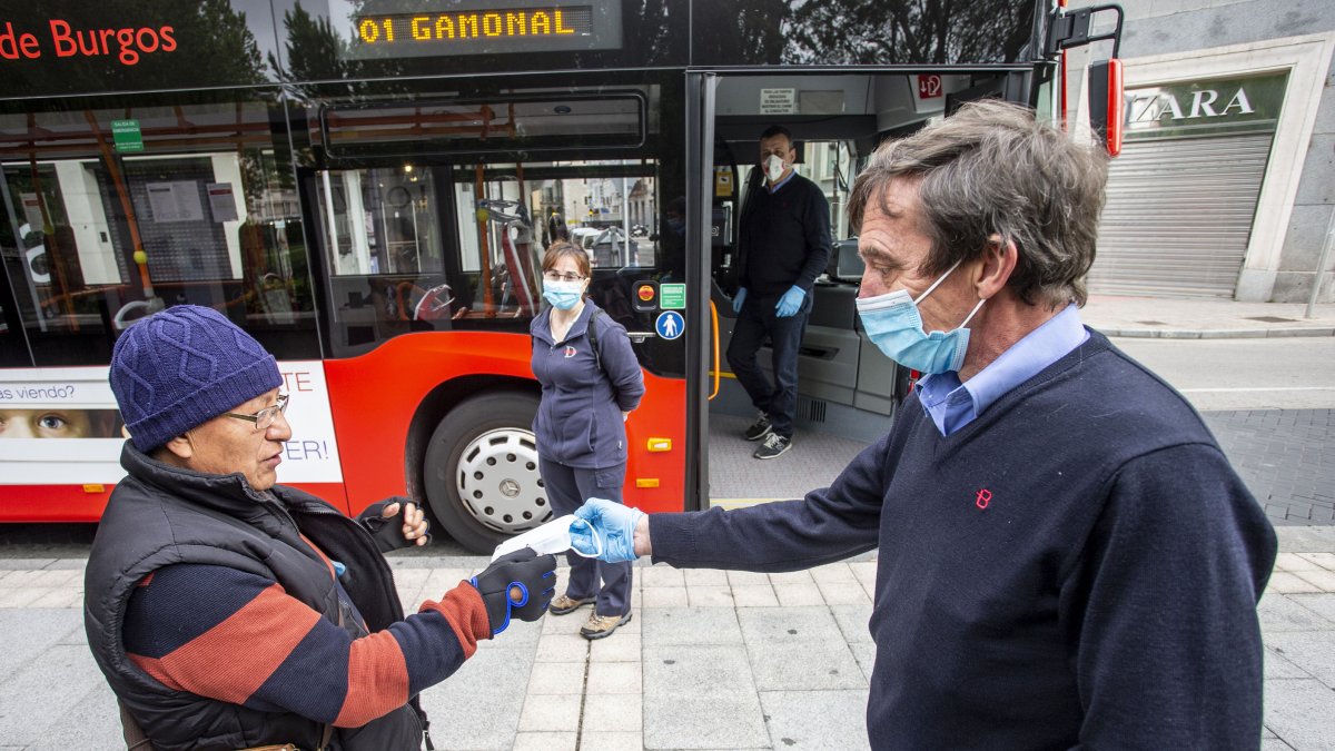 Un conductor de autobús entrega una mascarilla a un usuario del transporte público. SANTI OTERO