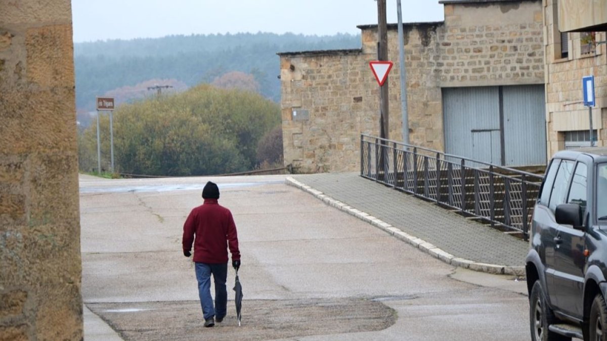 Un vecino de una localidad pinariega sale a la calle hoy viernes provisto de gorro y paraguas. R. F.