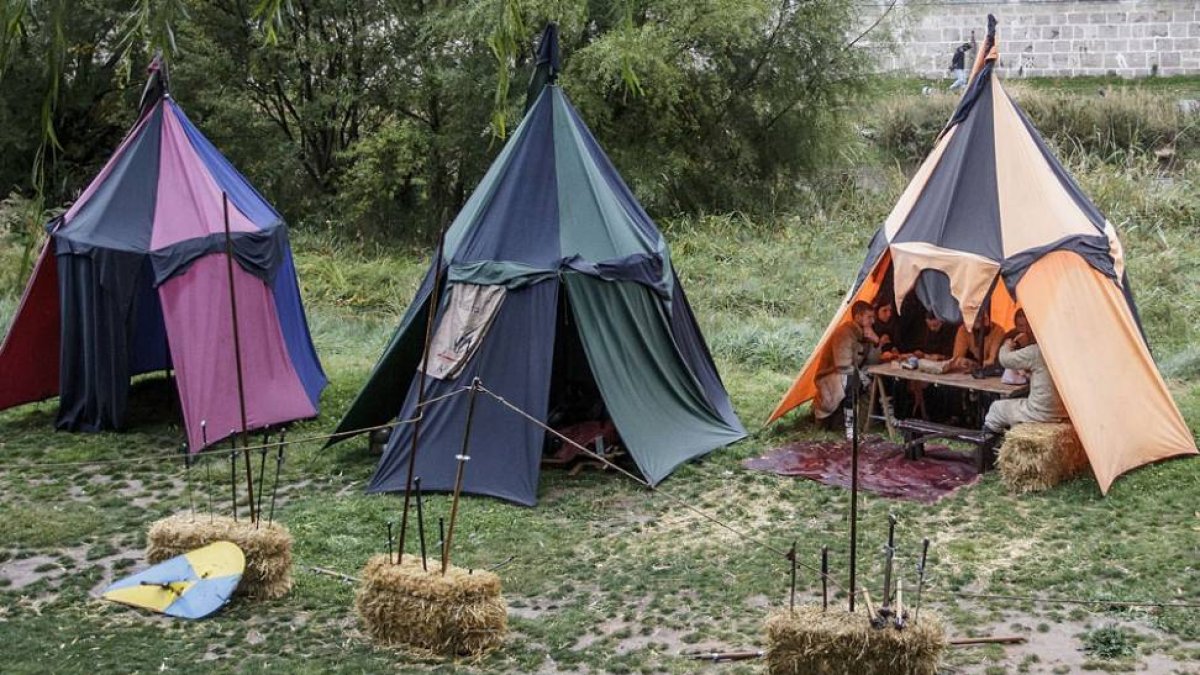 Los participantes de las actividades en la ribera del Arlanzón, ayer, protegidos de la lluvia en las tiendas.-SANTI OTERO