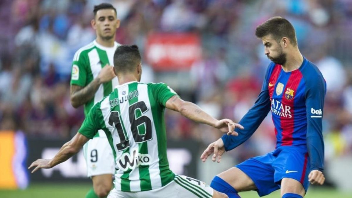 Piqué, junto a Cejudo, en el Barça-Betis de la primera jornada.-JORDI COTRINA