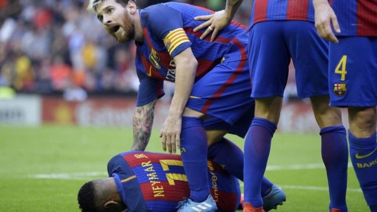 Neymar, atendido por Messi, se lamenta del lanzamiento de una botella de la grada de Mestalla.-AP / MANU FERNÁNDEZ