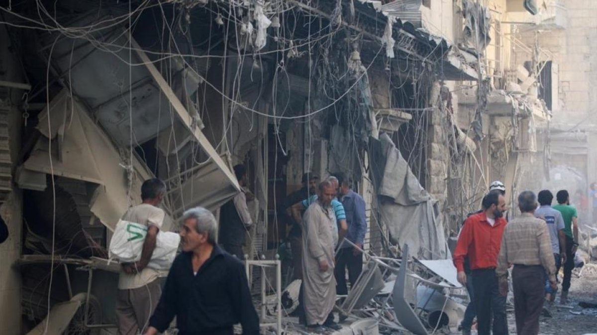 Miembros de la defensa civil siria y otras personas inspeccionan los edificios destrozados tras un bombardeo en el barrio de Al-Qaterji, controlado por los rebeldes, en Alepo, el 11 de octubre.-REUTERS / ABDALRHMAN ISMAIL