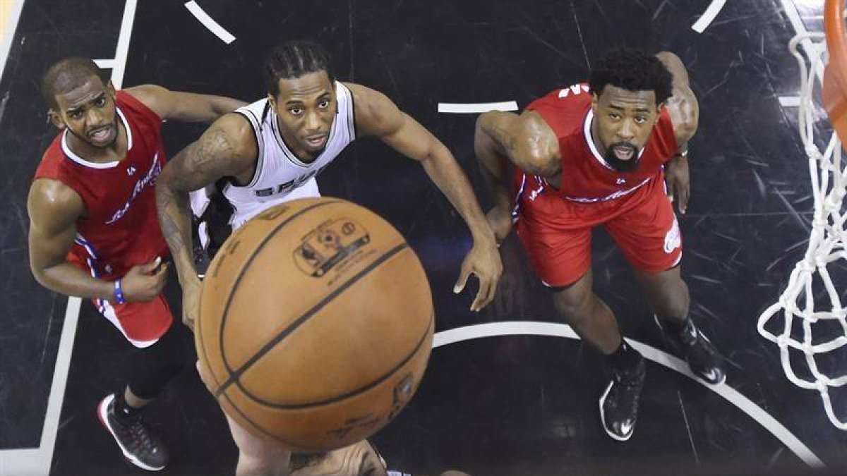Chris Paul (L) and DeAndre Jordan lucha por un rebote con Kawhi Leonard.-EFE