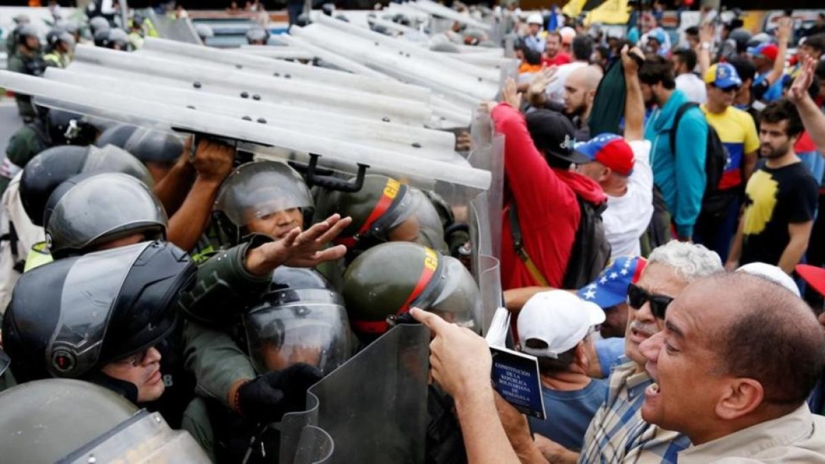 Opositores a Maduro se enfrentan a la Guardia Nacional en Caracas.-REUTERS / CARLOS GARCIA RAWLINS