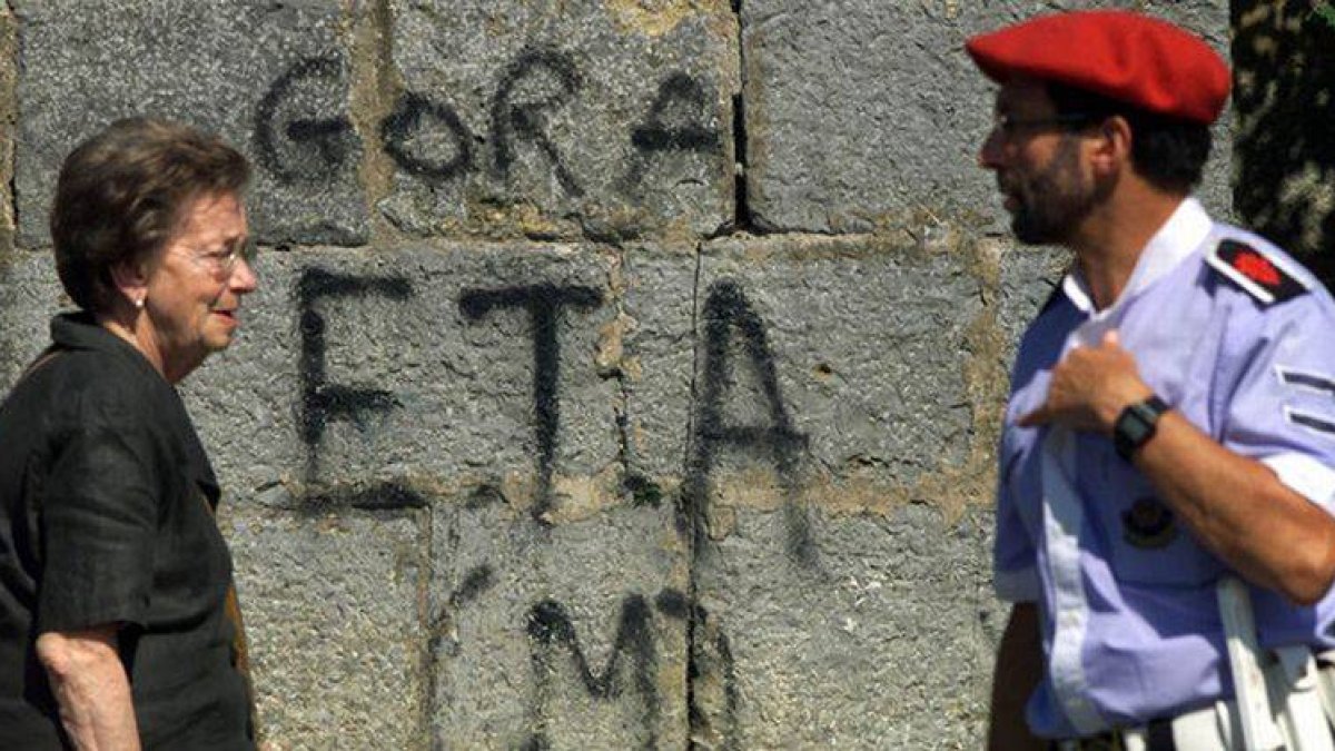 Una mujer y un erzaina pasan ante una pintada en favor de ETA.-ARCHIVO