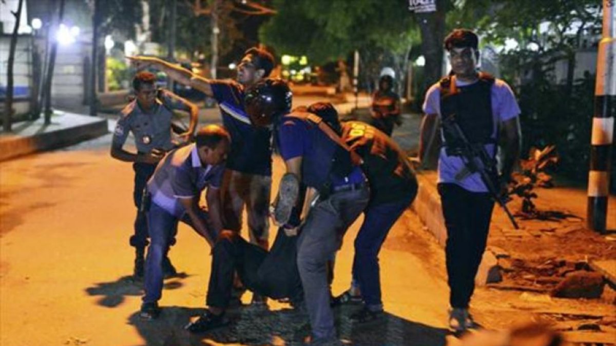 Un grupo de personas traslada a un herido en Dacca, anoche.-AP