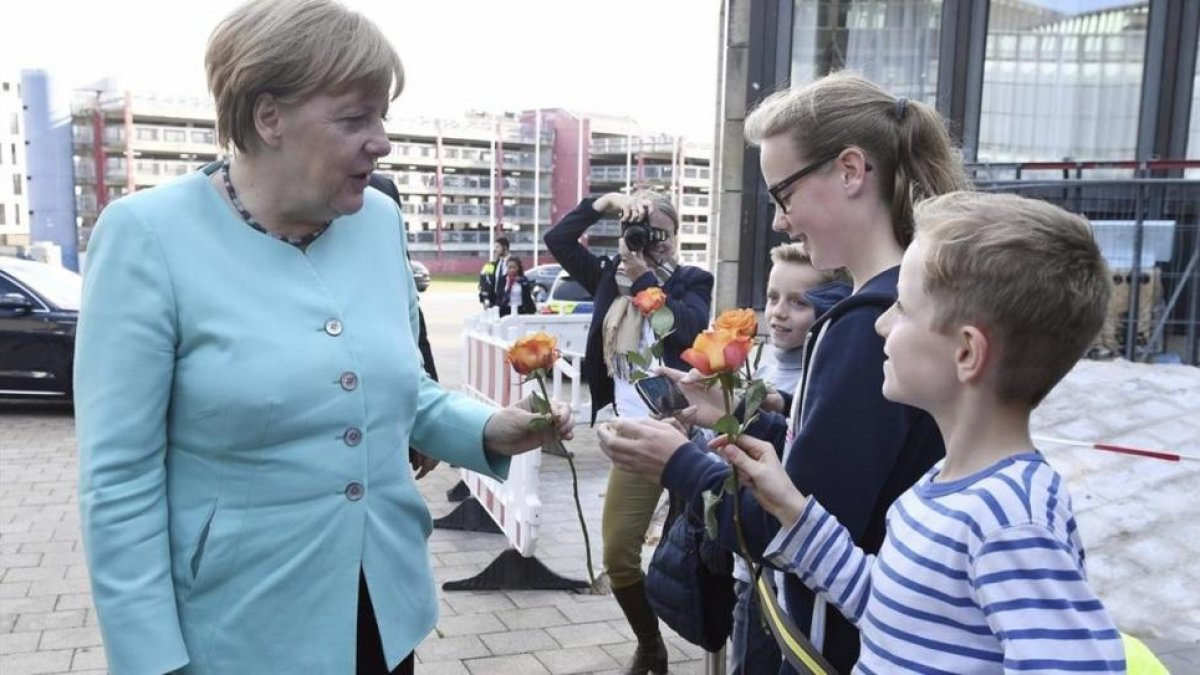 La cancillera Merkel, recibida con ramos de flores de niños a su llegada al Parlamento regional de Dusseldorf, con motivo del 70 aniversario de la CDU, el 30 de septiembre.-EFE / FEDERICO GAMBARINI