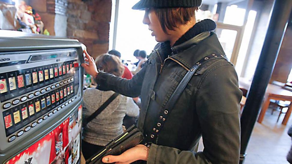 Una mujer compra tabaco en una máquina instalada en un bar.-ECB