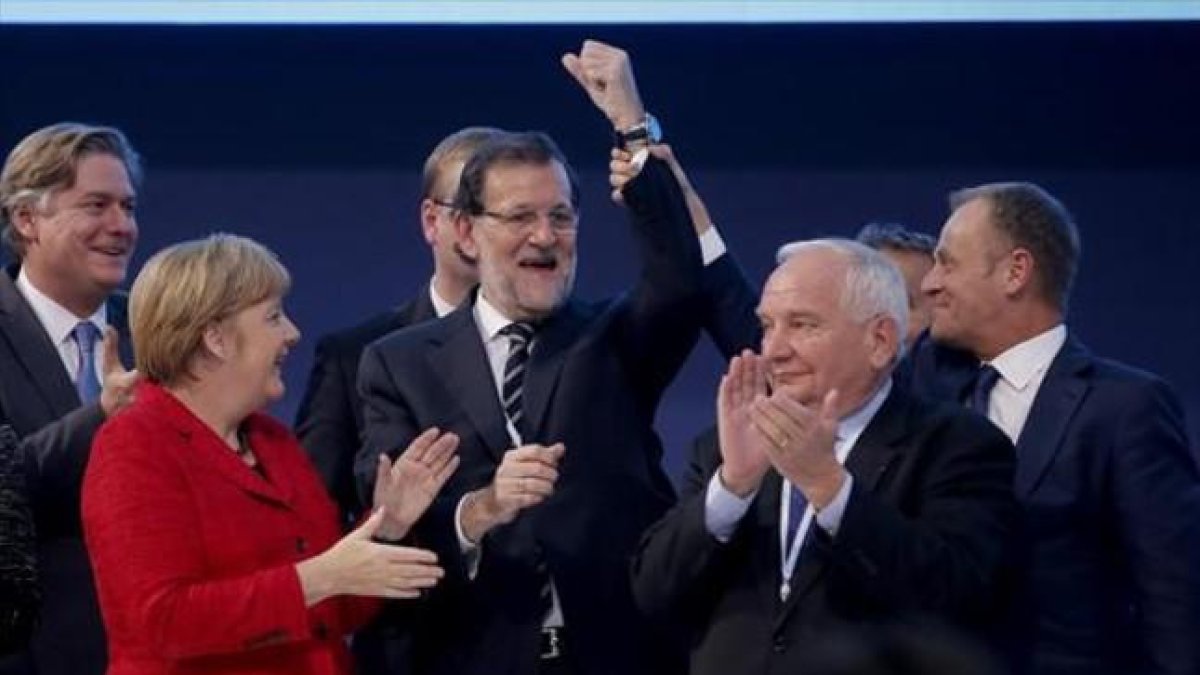 El presidente del Consejo Europeo, Donald Tusk, levanta el brazo de Rajoy en presencia de Angela Merkel y otros dirigentes populares europeos.-AGUSTÍN CATALÁN