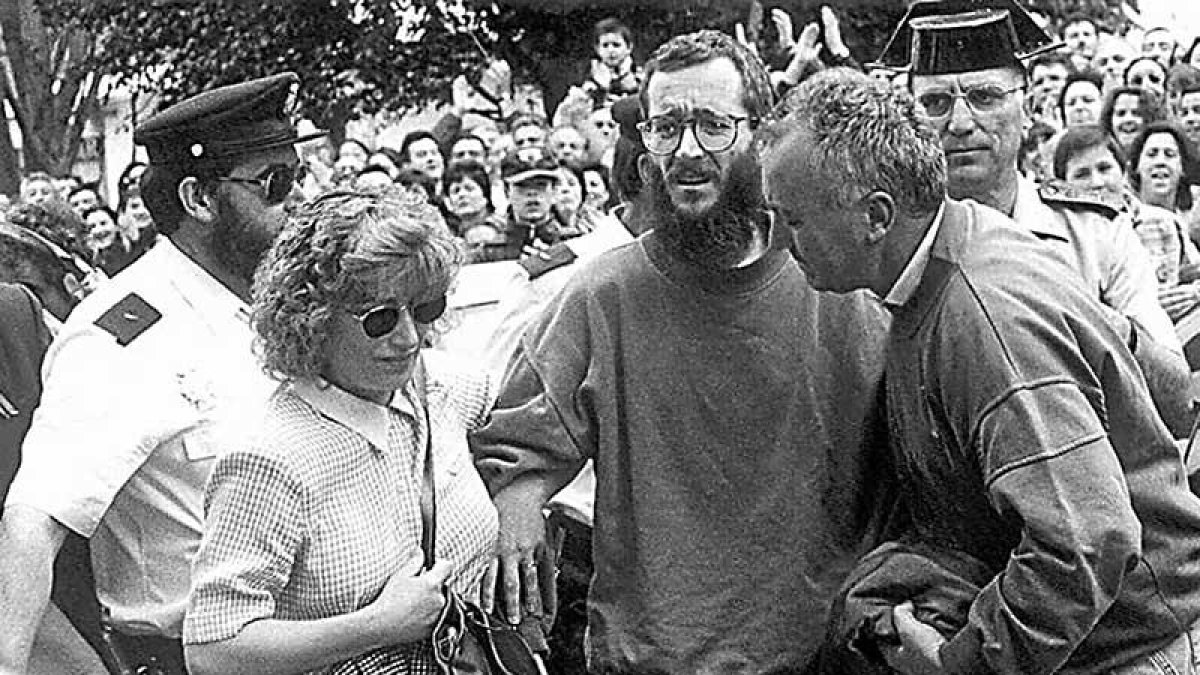 Domi, la esposa del funcionario de prisiones secuestrado, le ayuda a llegar al portal de su casa, rodeados de burgaleses que aplaudían su liberación. TOÑO GALLEGO