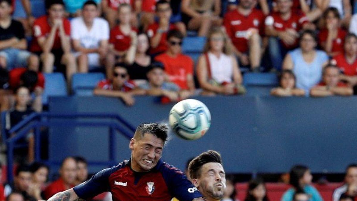 El delantero argentino de Osasuna Chimy Ávila (i) disputa un balón con Carles Pérez, del FC Barcelona, en el partido correspondiente a la 3ª Jornada de LaLiga Santander que Osasuna y FC Barcelona disputan hoy sábado en el estadio El Sadar, en Pamplona.-EFE