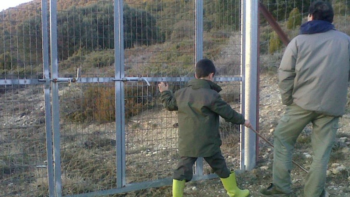 Un hombre y su hijo pasean junto a la valla que impide a la finca en la que se encuentran los pueblos abandonados de Fuente Humorera y Rioseco.-M.P.H.