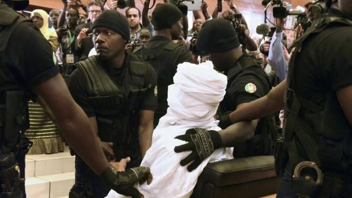 Habré, completamente tapado con una vestimenta blanca, rodeado de policías en el tribunal, en Dakar, este lunes.-Foto: AFP / SEILLOU