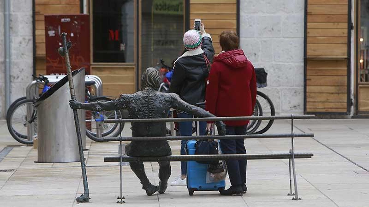 Dos turistas se fotografiaban ayer en la estatua del peregrino con la Catedral a su espalda.-RAÚL G. OCHOA