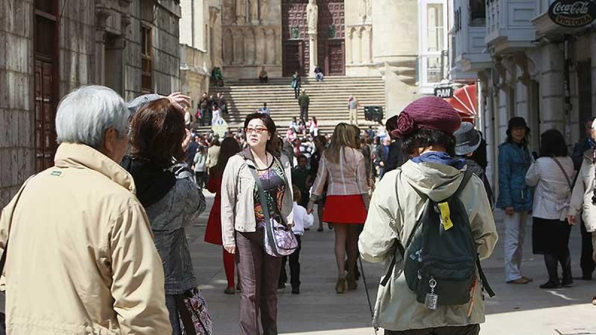 Un grupo de turistas asiáticos se fotografía en el Espolón con la puerta del Sarmental de fondo.-R. OCHOA
