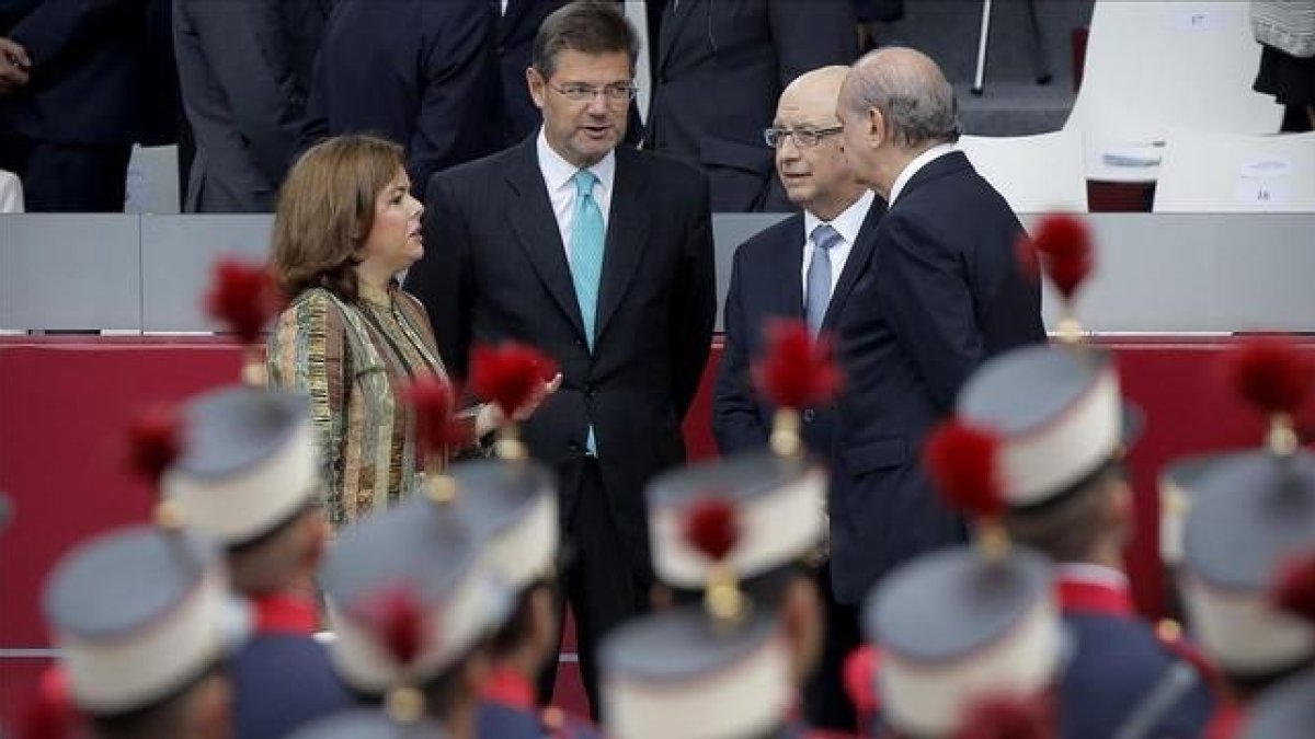 Cristóbal Montoro conversa con la vicepresidenta, Soraya Sáenz de Santamaría, y los ministros Rafael Catalá y Jorge Fernandez Diaz, durante el desfile del Día de la Hispanidad.-JOSÉ LUIS ROCA