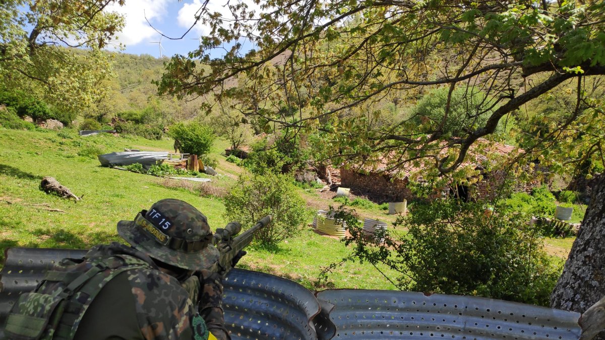 Un jugador de airsoft agazapado detrás de un obstáculo en una partida. LA FUNDICIÓN