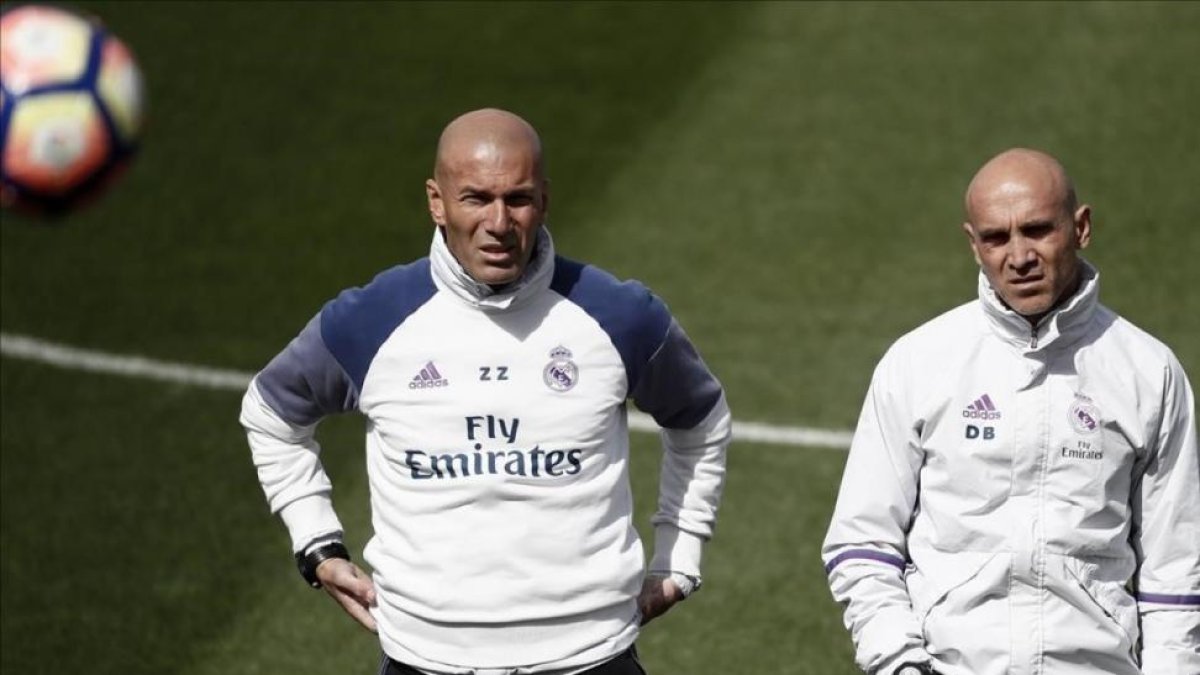 Zinedine Zidane, junto a su ayudante David Bettoni, en el entrenamiento de este sábado en Valdebebas.-EFE / MARISCAL