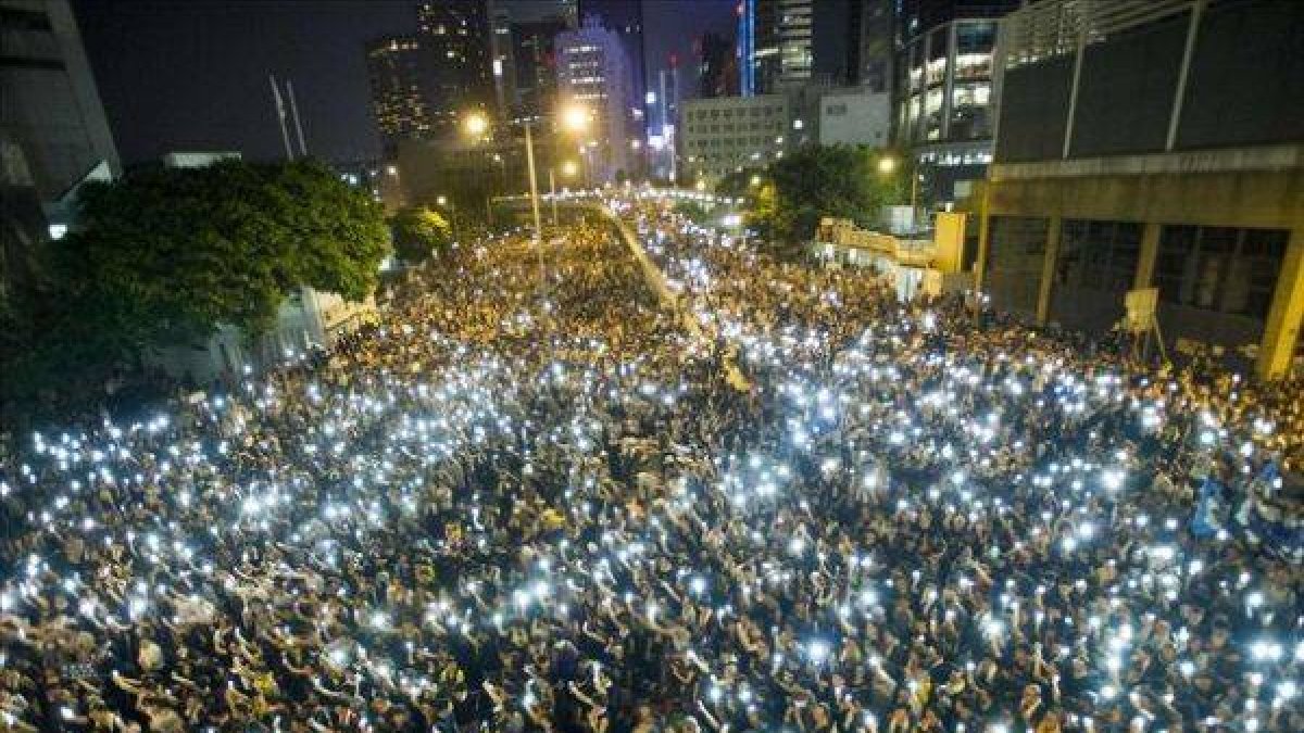 Manifestantes estudiantiles sostienen sus teléfonos en una muestra de solidaridad durante las protestas frente a la sede del Consejo Legislativo de Hong Kong.-Foto: AFP / XAUME OLLEROS