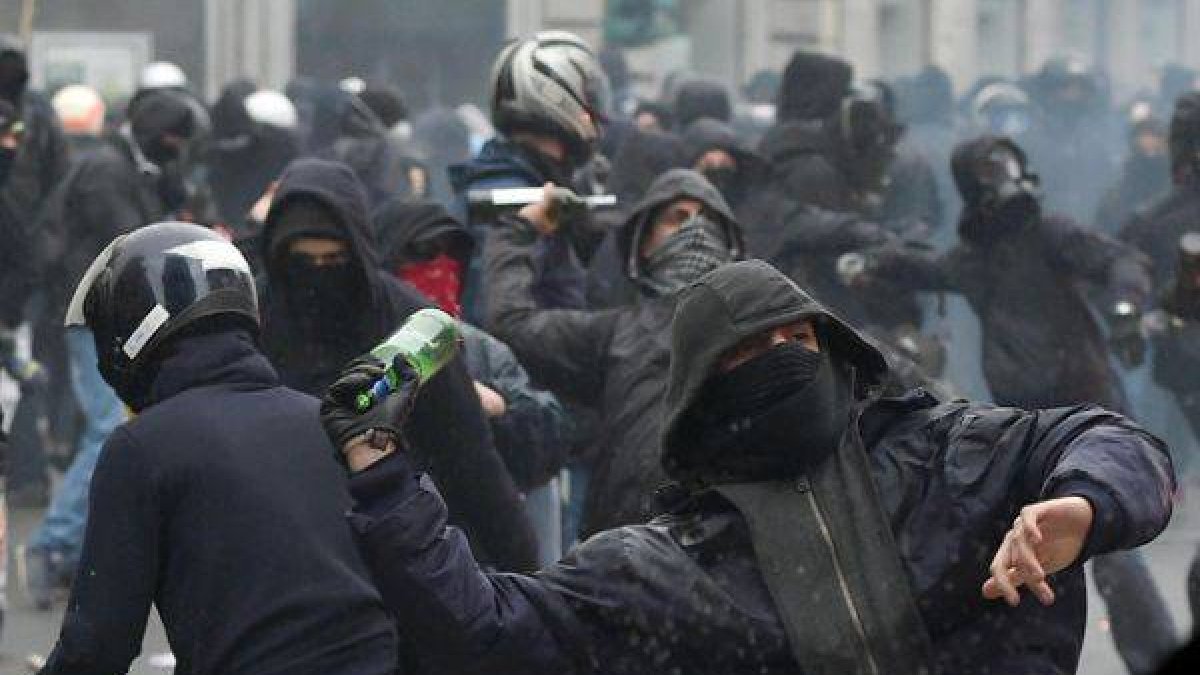 Manifiestantes antisistema lanzan botellas contra la policía italiana en Milán.-Foto: AP / DANIEL DAL ZENARO