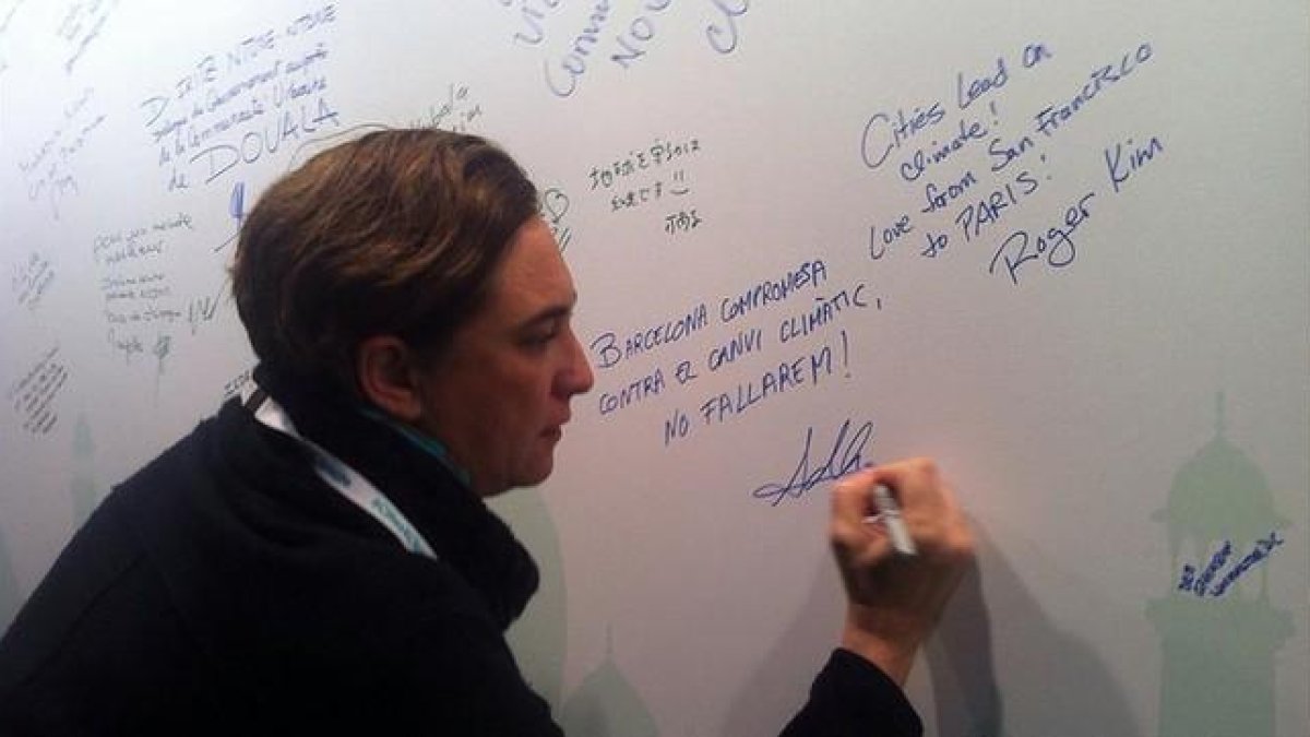 Colau firma en una pizarra su compromiso contra el cambio climático, en París, este viernes.-EL PERIÓDICO