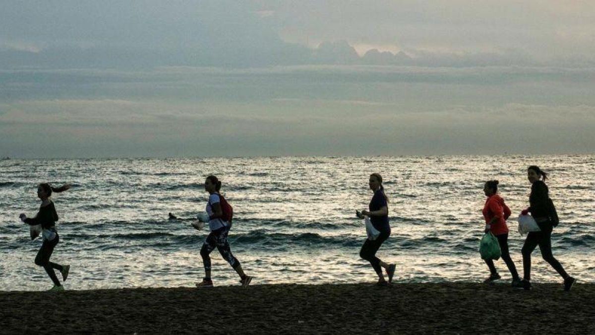 Miembros de Barcelona Plogging, al amanecer en la Barceloneta. Antes de correr, te dan una bolsa biodegradable y un par de guantes. La próxima quedada es el 7 de noviembre.-JOAN CORTADELLAS