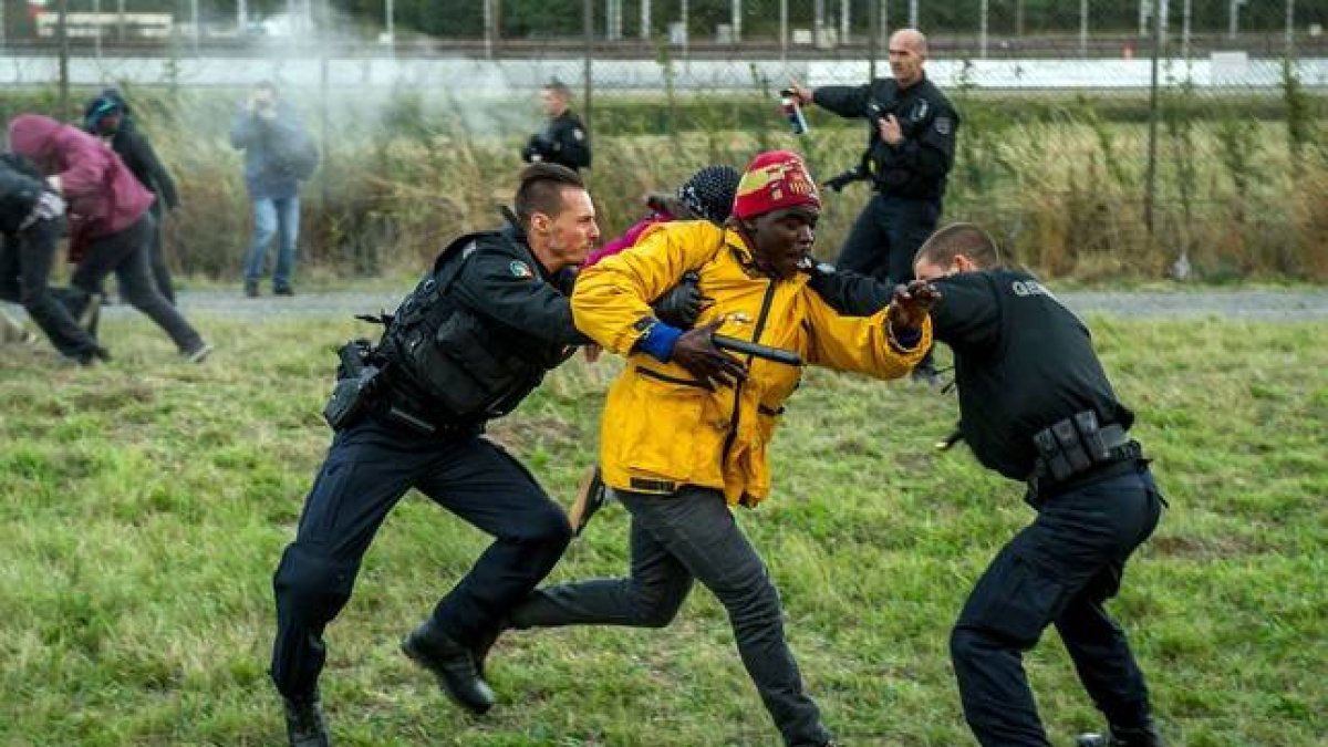 Policías franceses intentan parar a los inmigrantes que buscan colarse al Eurotúnel en Calais este miércoles.-Foto: AFP / PHILIPPE HUGUEN