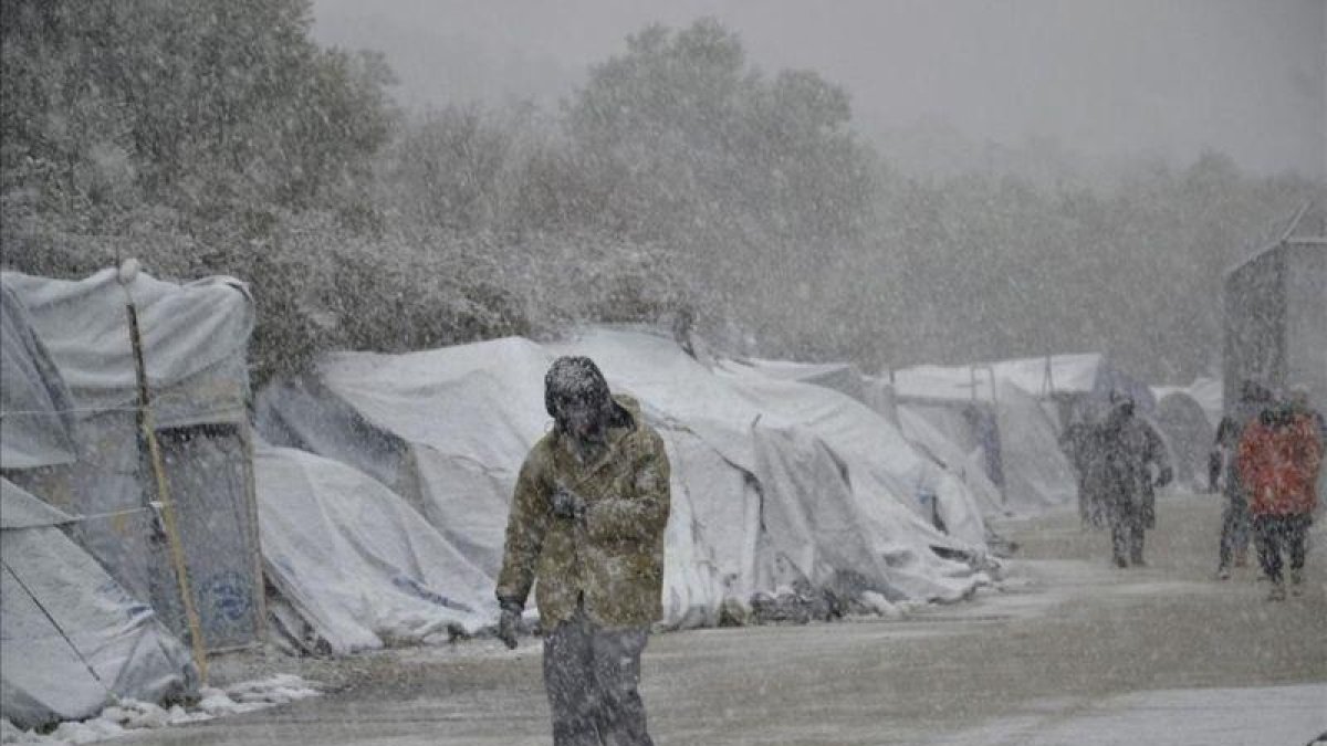 Varios refugiados caminan bajo la nieve en el campamento de refugiados de Moria en la isla de Lesbos, Grecia.-EFE / STRATIS BALASKAS
