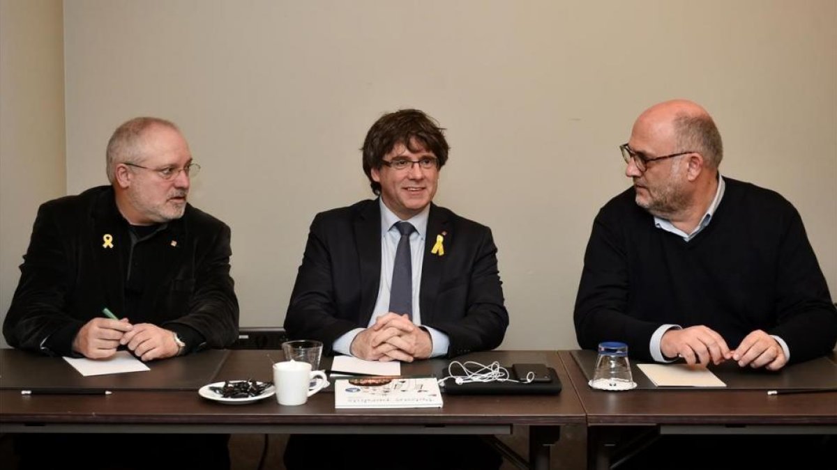 Puigdemont franqueado por su ex consejeros Lluis Puig y Eduard Pujol-JOHN THYS (AFP)