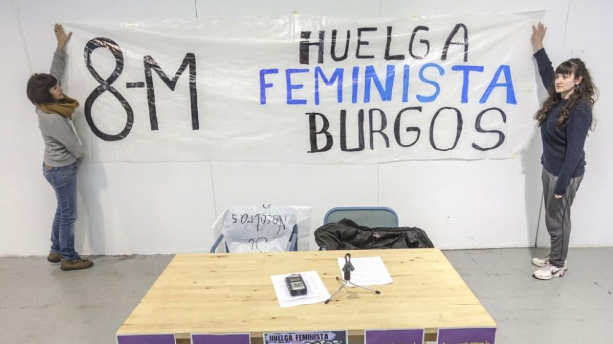 Dos integrantes de la asamblea colocan una pancarta momentos antes de iniciar la rueda de prensa.-SANTI OTERO