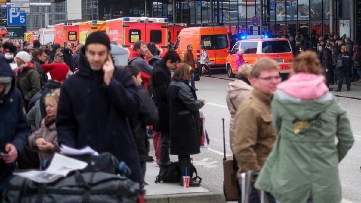 Bomberos y pasajeros evacuados del aeropuerto de Hamburgo.-AXEL HEIMKEN