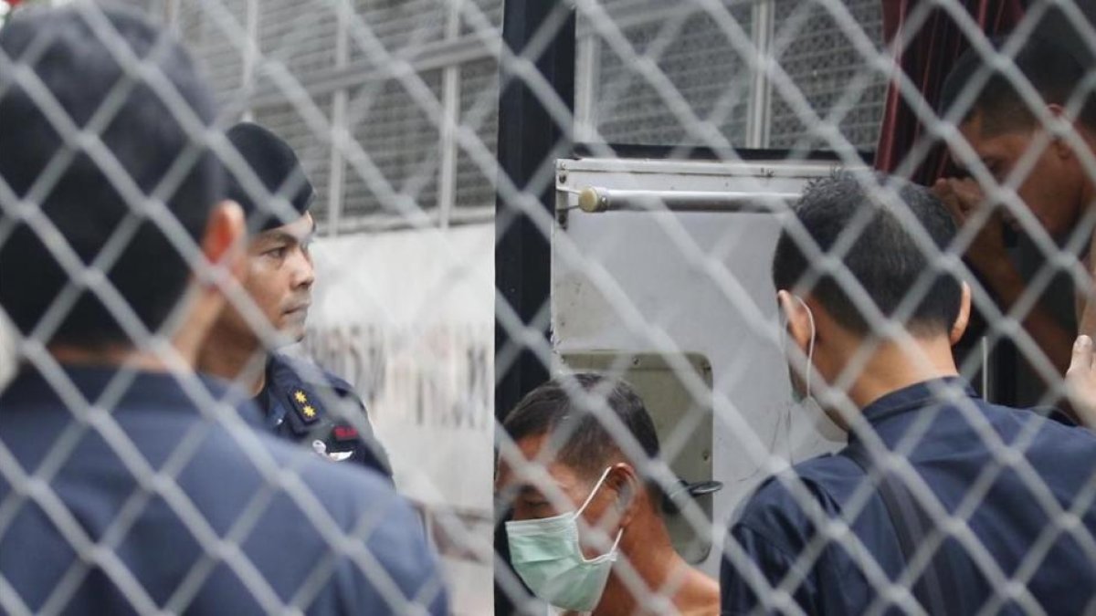 Agentes de policia tailandeses custodian la llegada de un sospechoso de trata de personas en el tribunal penal de Bangkok este miércoles-NARONG SANGNAK