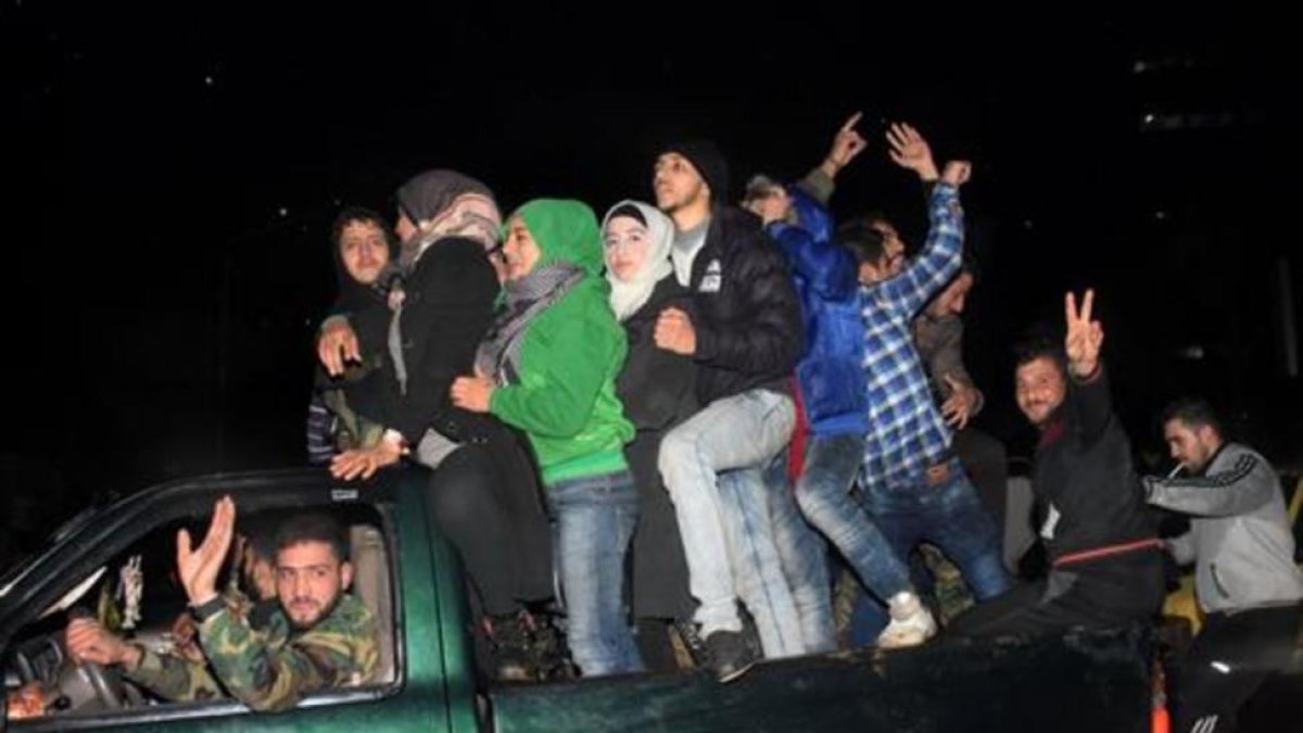 Un combatiente progubernamental carga a una mujer herida por un disparo rebelde cuando huía del barrio de Al Salhín, en Alepo.-AFP / GEORGE OURFALIAN