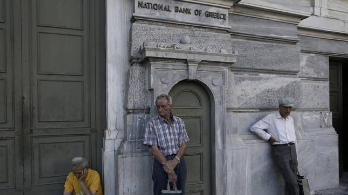 Pensionistas esperan para cobrar frente a un banco de Atenas (Grecia).-Foto: EFE / YANNIS KOLESIDIS