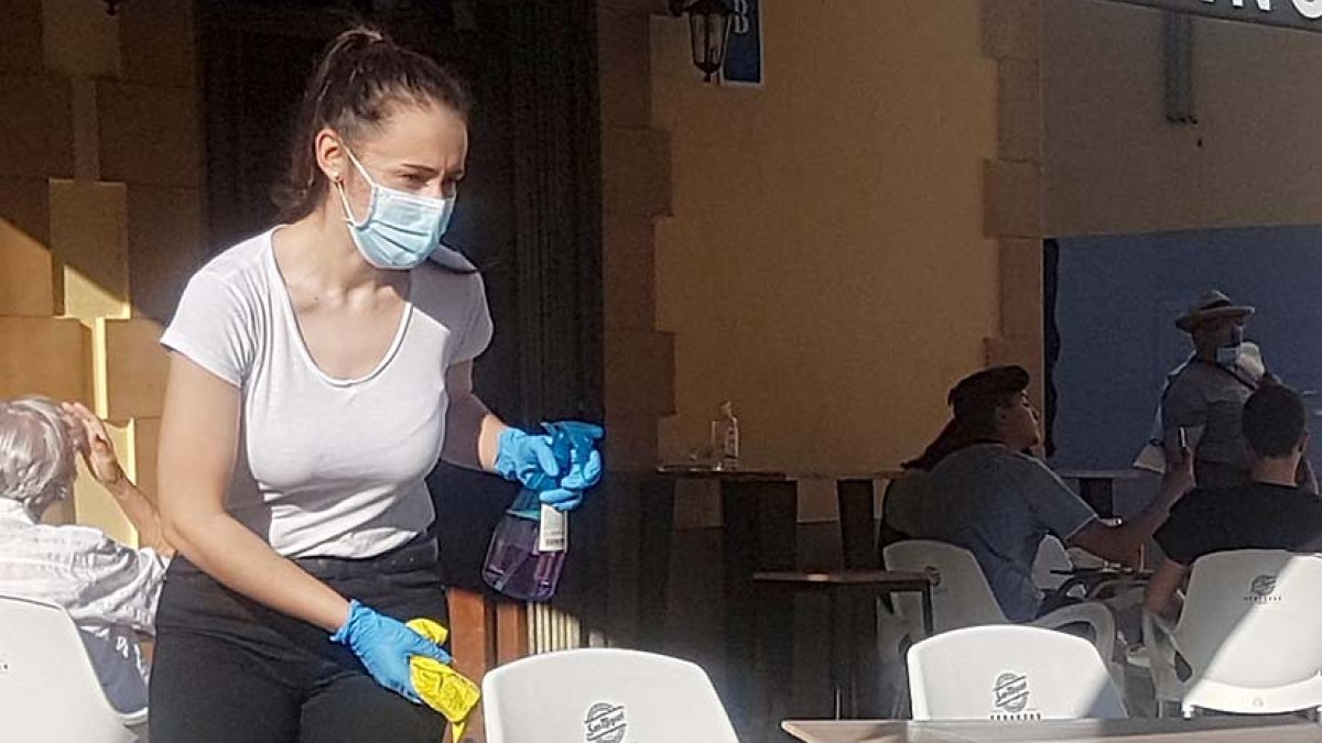 Una camarera limpia y desinfecta una mesa en un bar de Aranda. L. V.