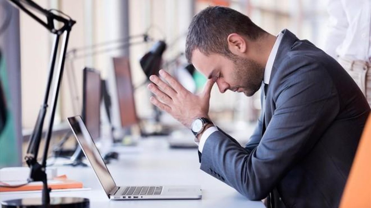 Un chico en la oficina sin poder trabajar.-123RF