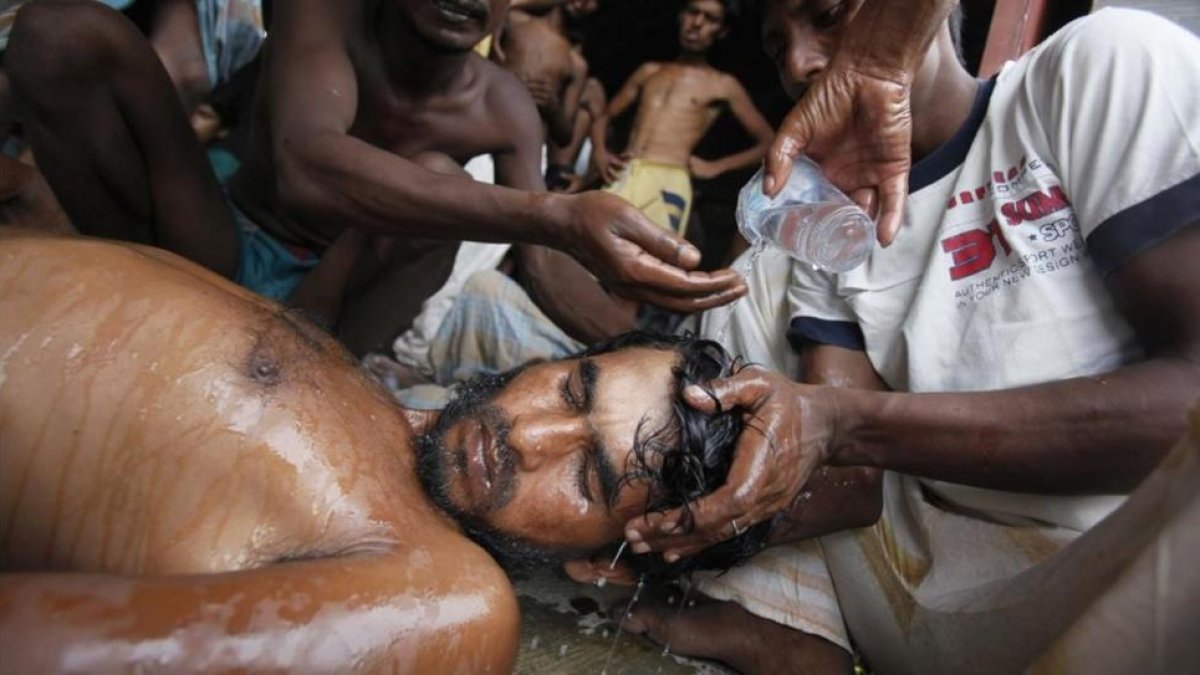 magen de archivo de 2015 que muestra a un grupo de hombres socorren a un rohingya en Indonesia tras haber huido de Birmania.-