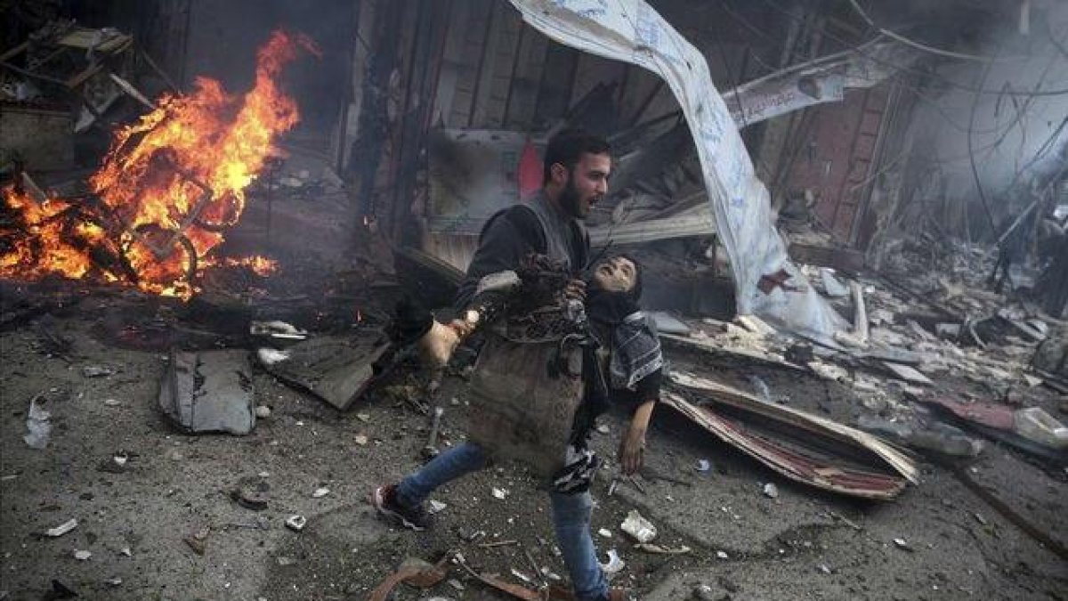 Un hombre sirio portando el cuerpo sin vida de un niño asesinado durante los bombardeos efectuados en la ciudad de Douma,  Siria.-ABD DOUMANY