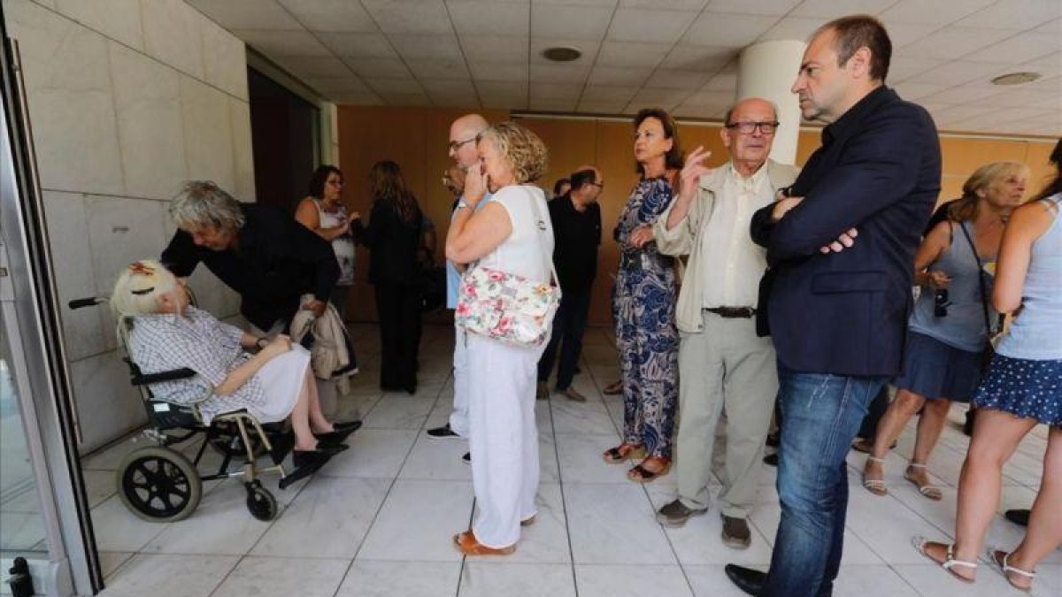 Paco Ibáñez se despide de la viuda de Víctor Mora en presencia de Francisco Ibáñez y del directivo del Grupo Zeta Román de Vicente (derecha).-JOSEP GARCIA