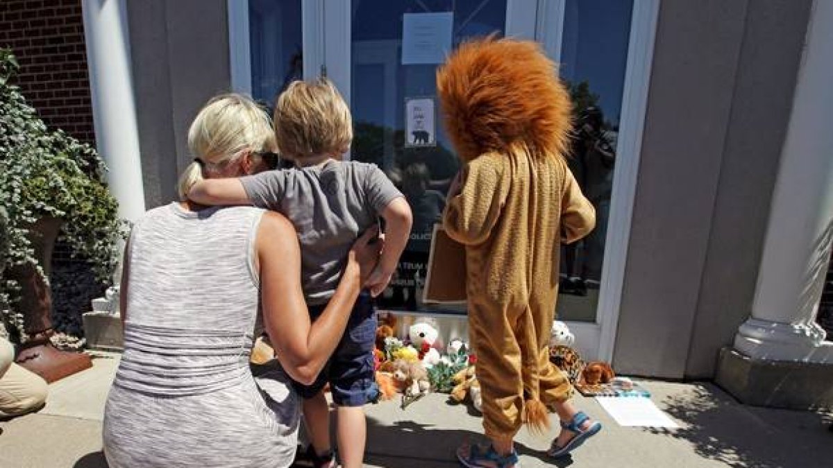 Niños lloran la muerte de Cecil, ante la puerta de la clínica del dentista que lo mató, en Bloomington (Minneápolis).-Foto:   ERIC MILLER / REUTERS