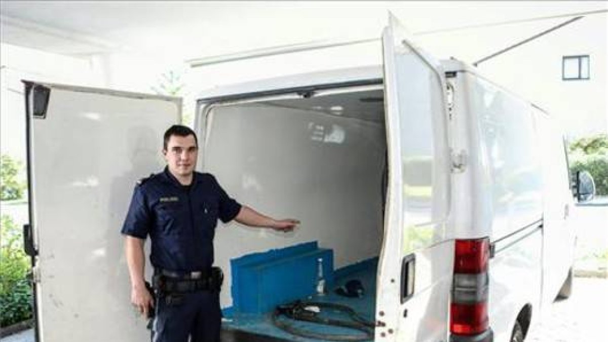 Un agente austriaco muestra la camioneta en la que viajaban los tres niños hallados en estado grave, este sábado, en Braunau (Austria).-DANIEL SCHARINGER / EFE