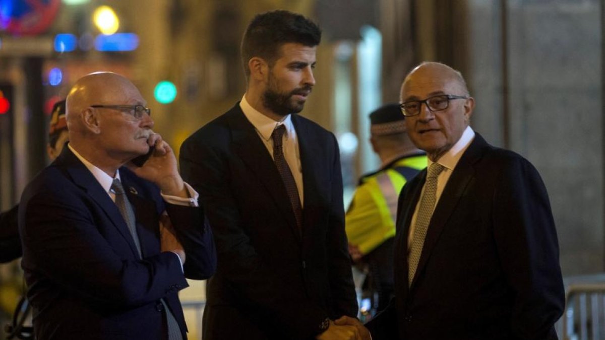 Gerard Piqué (c) saluda al presidente del Banco de Sabadell, Josep Oliu (d), en presencia del CEO y consejero delegado del GSMA, John Hoffman (i) tras la cena de bienvenida al Mobile World Congress (MWC).-QUIQUE GARCÍA (EFE)