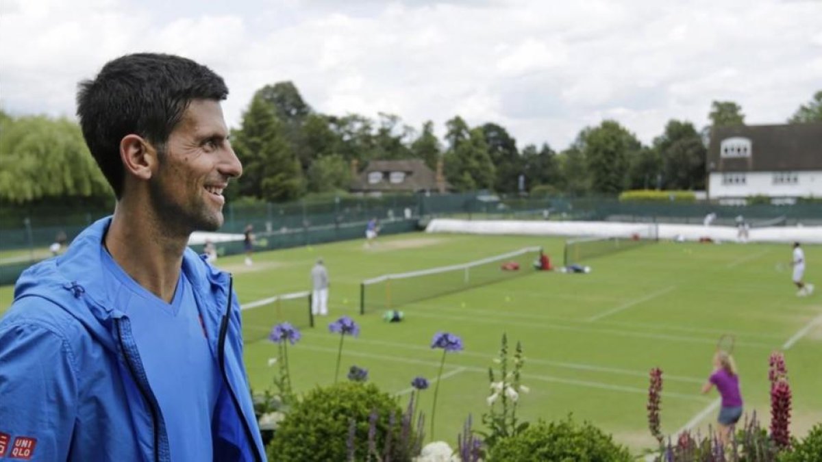 Djokovic observa las pistas de Wimbledon tras el entrenamiento del domingo.-AP / BEN CURTIS