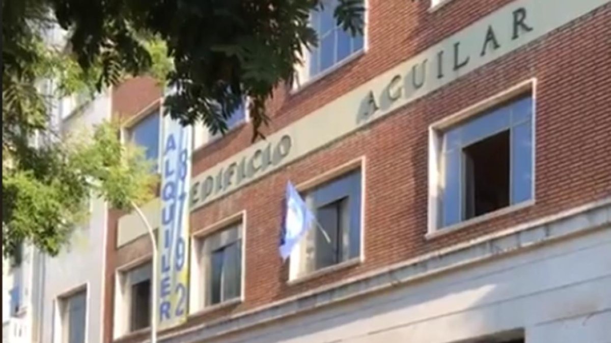 El emblema de Hogar Social Madrid ondea en una de las ventanas del nuevo edificio okupado, las antiguas oficinas de la Editorial Aguilar. /-PERIODICO