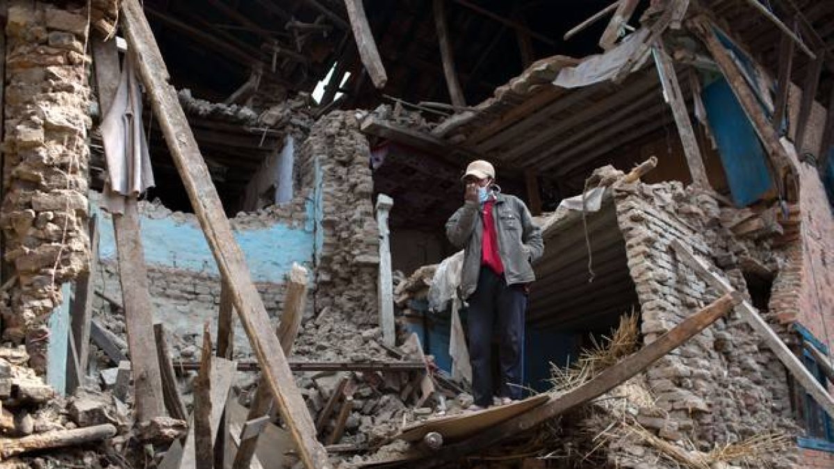 Un hombre en pie entre las runas de un edificio destruido por el terremoto de Nepal.-Foto: MENAHEM KAHANA / AFP